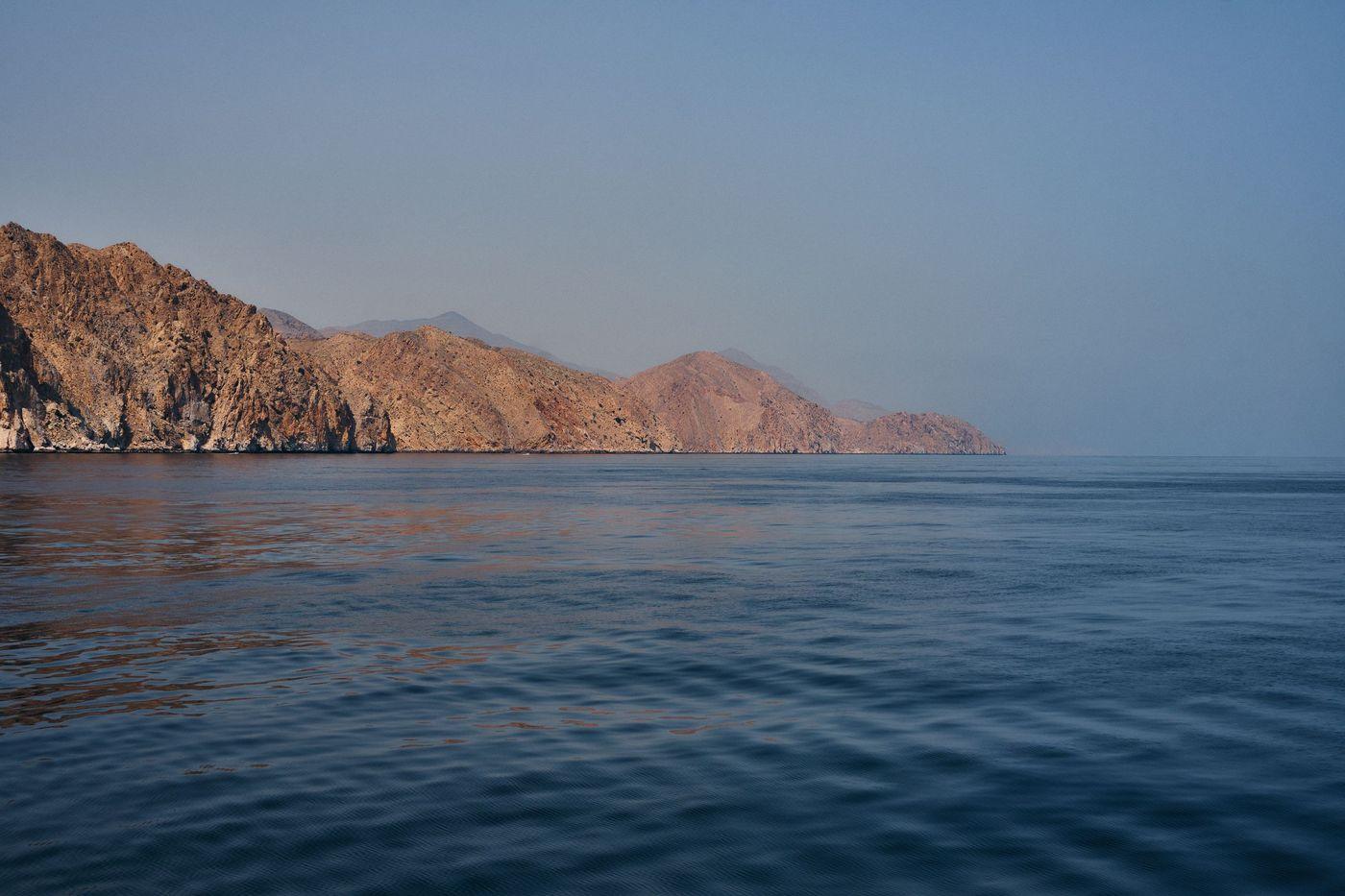 Rocky arid coastline meeting calm turquoise sea under a clear sky