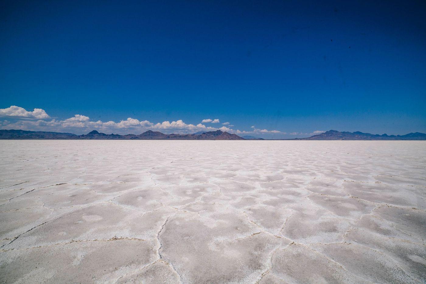 A vast white salt crust stretching towards distant mountains under a clear sky